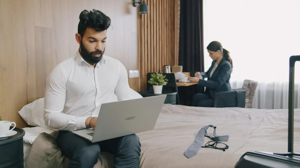 Pelancong bekerja dengan laptop di kamar hotel